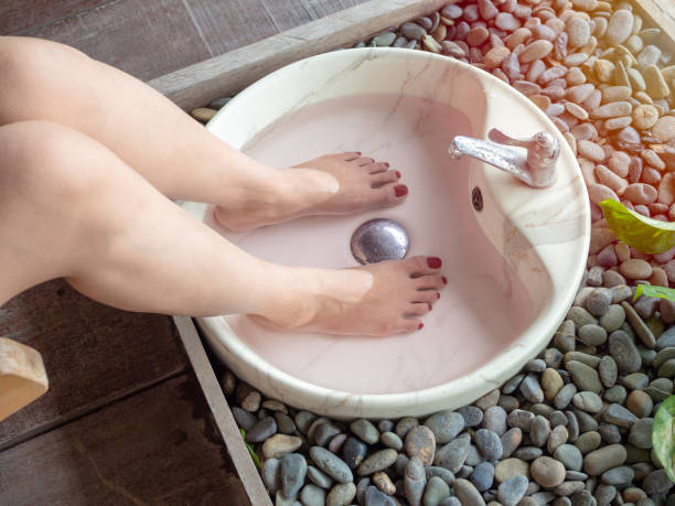 Female feet in foot spa marble basin. epsom salt foot soak concept.